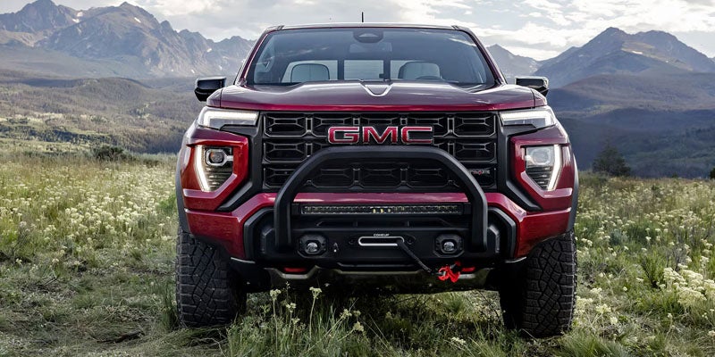 2026 GMC Canyon AT4X red midsize pickup truck parked in a mountain landscape