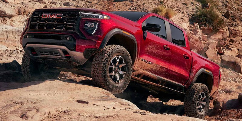 2026 GMC Canyon AT4X red off-road truck climbing rocky terrain